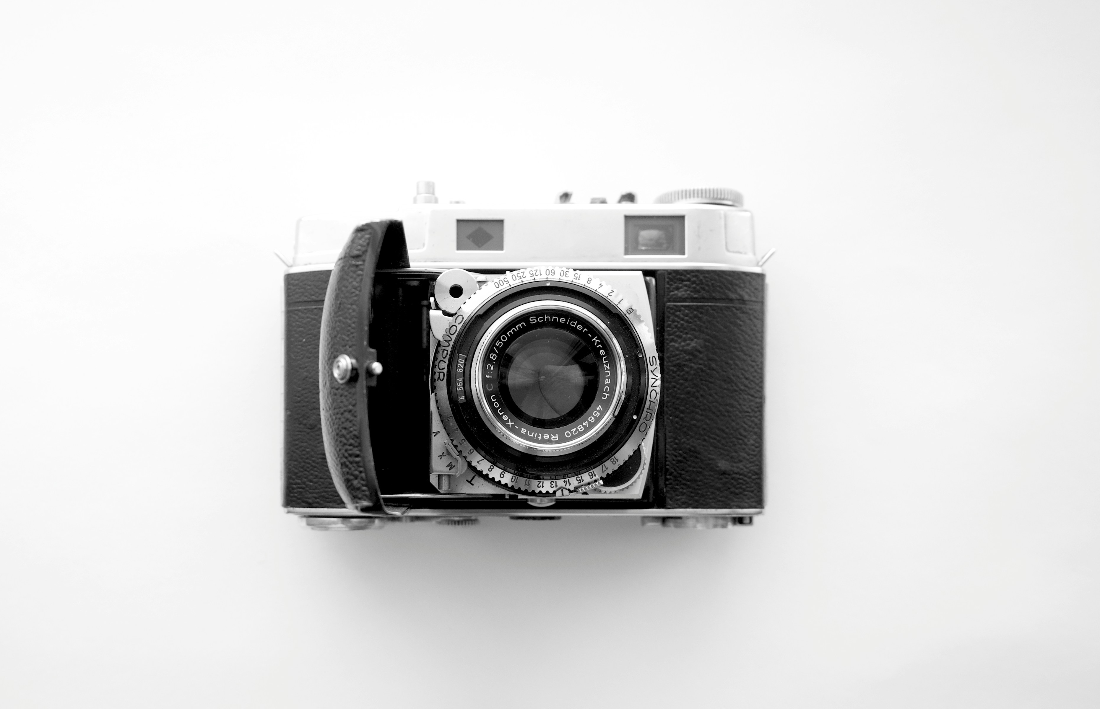 A camera used to take photos with Kodak films inside.  Kodak digital camera with a black body placed on a wall or white surface. 